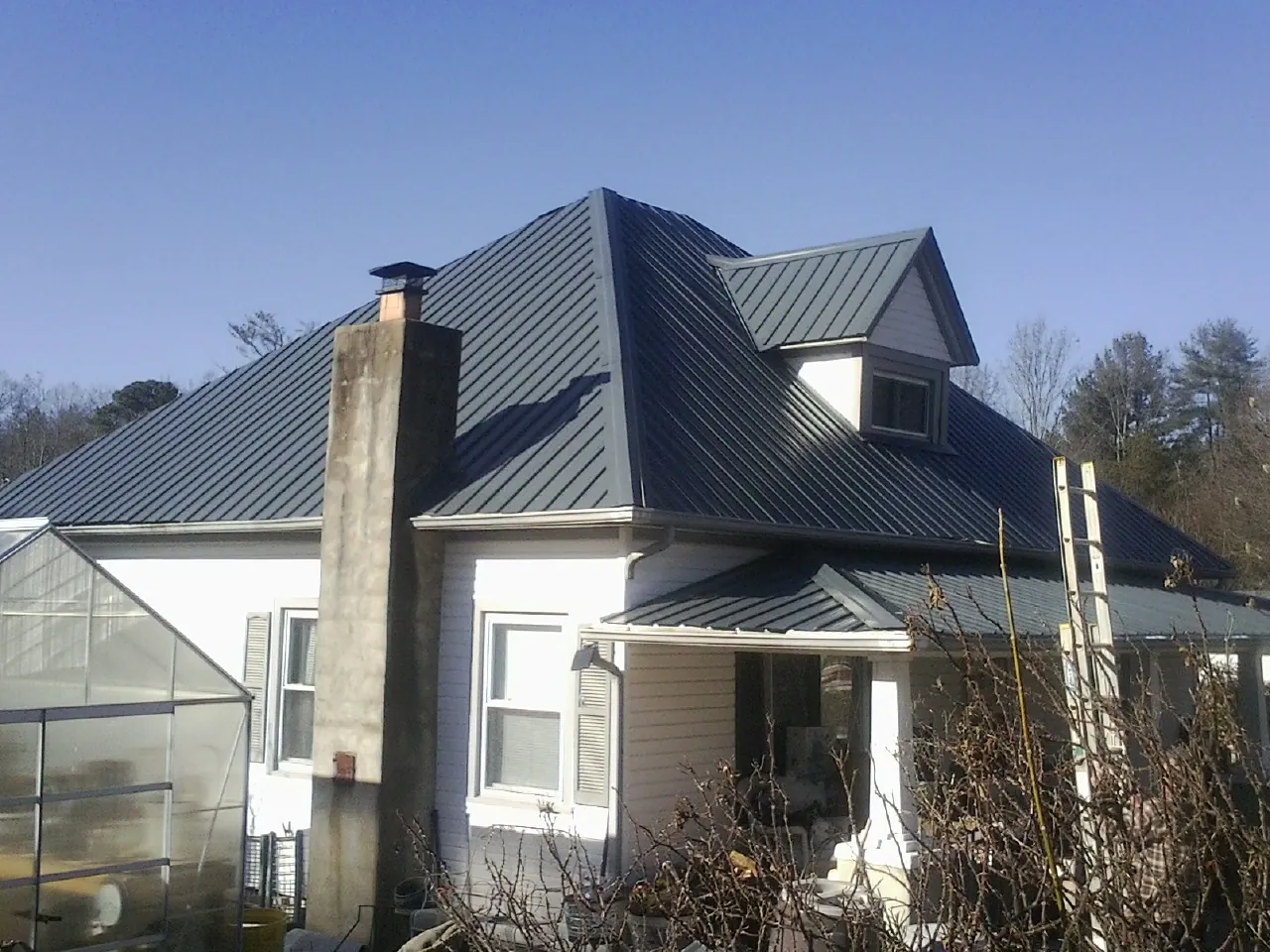 Dark blue standing seam metal roof on a white farmhouse with dormer — Slate & Tile Roof Repair by Roofing Brothers in San Fernando