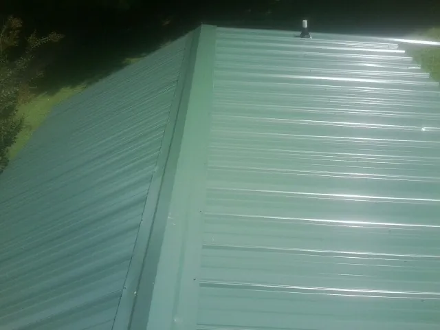 New green metal panels meeting at the ridge of a roof — Flat Roof Repair work by our crew in San Fernando