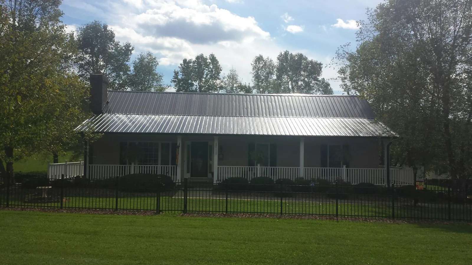 Gray metal roof on a brick ranch with a full width front porch — Gutter Guard Installation work by our crew in San Fernando