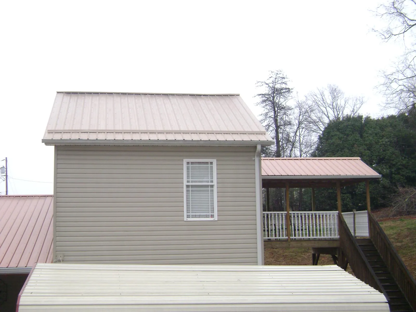Tan metal roofs on a two story addition and attached porch, from a Roof Replacement job in San Fernando