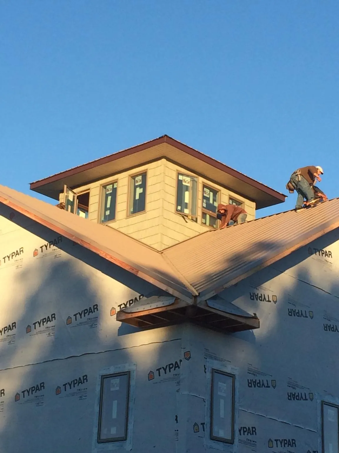 Roofers working around a rooftop cupola on a new metal roof at sunset — Roof Waterproofing in San Fernando by Roofing Brothers